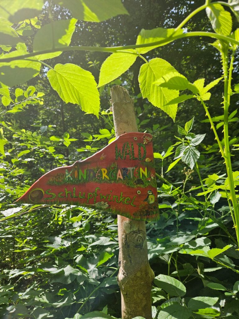Schild des Waldkindergartens Schlupfwinkel an einem Baum